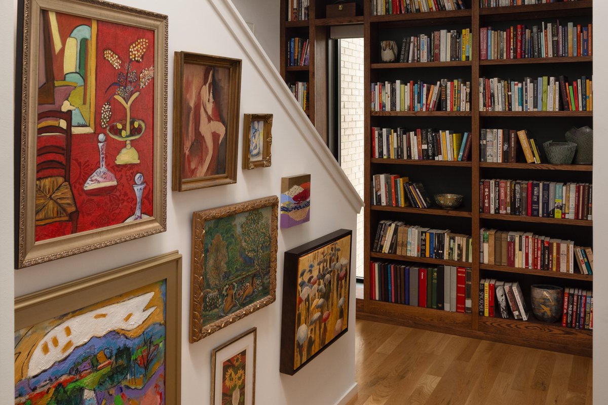 A stairwell hall with a floor-to-ceiling gallery wall and a built-in library