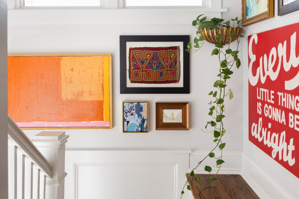 A stairway with a floor-to-ceiling gallery wall, a wood ledge, and a trailing pothos